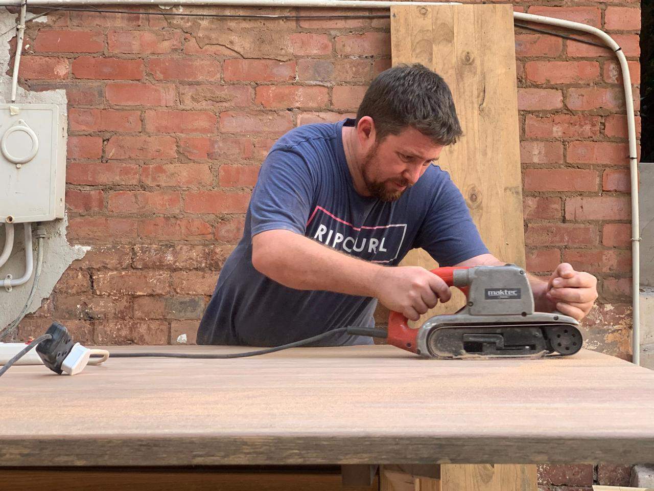 David sanding the hardwood table during the DG Technologies showroom build